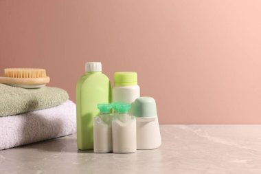 Bej duvarın yanındaki gri masada farklı banyo ürünleri var. Metin için boşluk