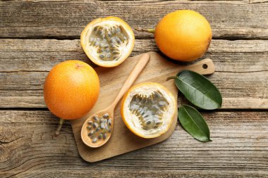 Olgun çarkıfelek meyveleri, tohumlar ve yeşil yapraklar ahşap masada, düz yatıyordu.