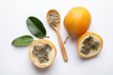 Olgun tutku meyveleri, tohumlar ve yeşil yapraklar beyaz arka planda, düz yatıyordu