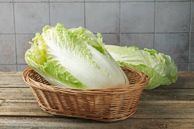 Hasır sepetin içinde taze Çin lahanaları ahşap masanın üzerinde, yakın plan.