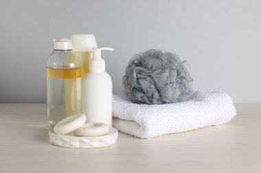 Açık ahşap masada gri arka planda farklı banyo aksesuarları, yakın plan.