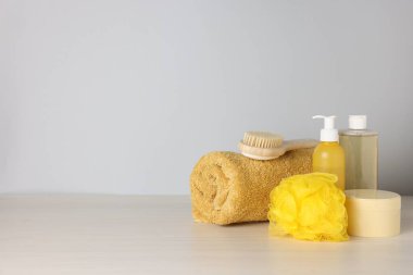 Açık ahşap masada gri arka planda farklı banyo aksesuarları. Metin için boşluk