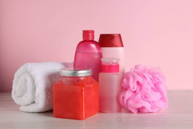 Açık ahşap masa üzerinde farklı banyo aksesuarları, pembe arka plan, yakın çekim