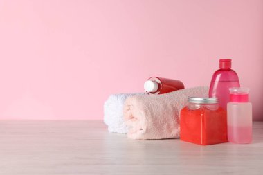Pembe arka planda açık ahşap masada farklı banyo aksesuarları. Metin için boşluk