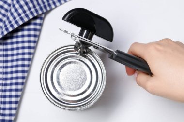 Beyaz masada konserve açacağıyla konserve açan kadın, üst manzara