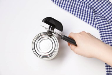 Beyaz masada konserve açacağıyla konserve açan kadın, üst manzara