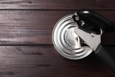 Konserve açacağı ve teneke kutu, ahşap masa, üst manzara. Metin için boşluk