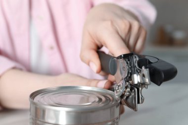 Beyaz masada konserve açacağıyla konserve açan kadın, yakın çekim