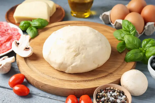 Pizza yapıyorum. Gri ahşap masadaki farklı malzemeler, yakın plan.