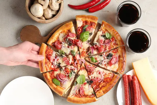 Işık masasında ince tütsülenmiş sosisle lezzetli bir pizza yiyen bir kadın.