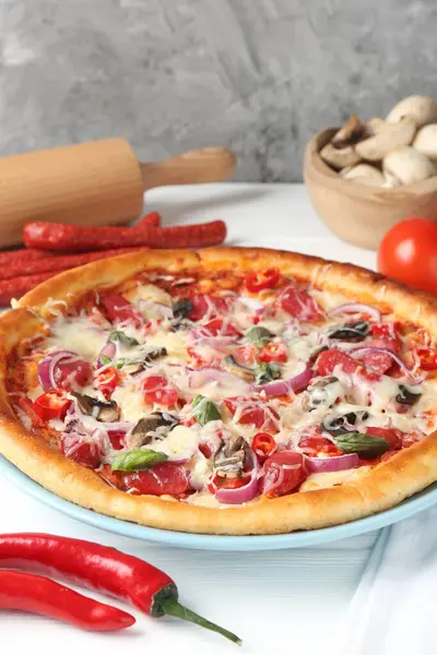 İnce tütsülenmiş sosis ve malzemelerle dolu leziz bir pizza, yakın plan.