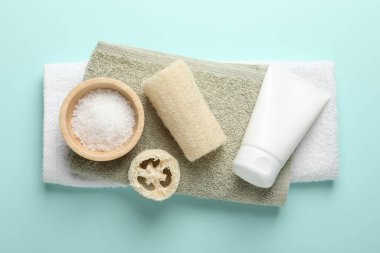 Doğal lif süngeri, kozmetik ürünleri ve açık mavi arka planda havlular, üst manzara.