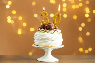 30. yaş günü. Tahta sehpanın üzerinde yanan mumlarla bulanık arka planda ışıklar ve bokeh efekti olan lezzetli bir kek.