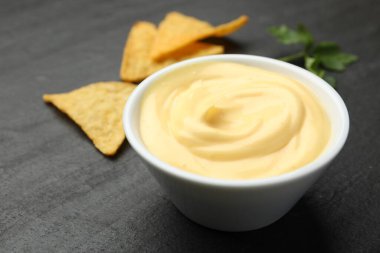 Lezzetli bir peynir sosu, siyah masada nacho cipsi ve maydanoz, yakın plan. Metin için boşluk