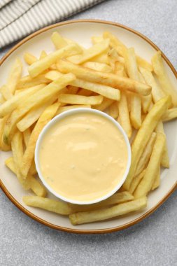 Lezzetli peynir sosu kasede ve patates kızartması gri masada.