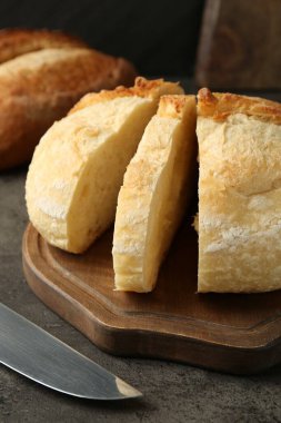 Farklı türde taze ekmek ve bıçak koyu dokulu masa, yakın plan.