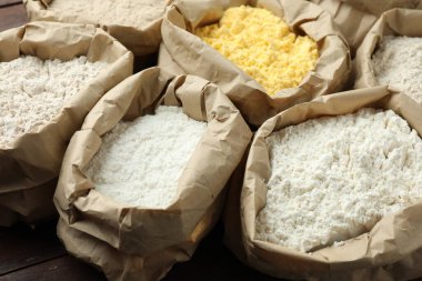 Tahta masadaki kağıt torbalarda farklı türde un, yakın plan.