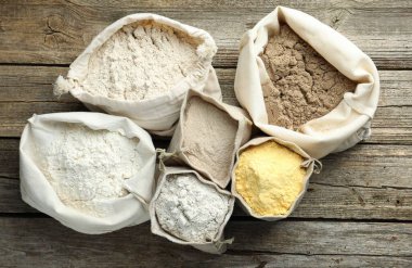 Tahta masada, düz bir zeminde, çuvalda farklı türde un bulunur.