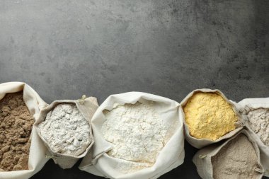 Gri masadaki poşetlerdeki farklı tipte un, düz. Metin için boşluk