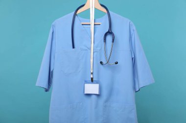 Steteskop ve rozetli sağlık çalışanı üniforması mavi arka planda.