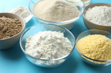 Açık mavi arkaplanda farklı un türleri, yakın plan