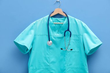 Mavi arka planda steteskop takılı sağlık çalışanı üniforması.