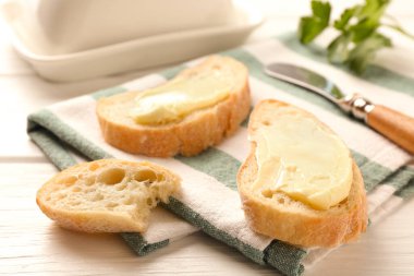 Beyaz ahşap masada tereyağlı ekmek dilimleri, yakın plan.
