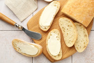 Tereyağlı ve bıçaklı ekmek parçaları. Işık döşeli masa, üst manzara.