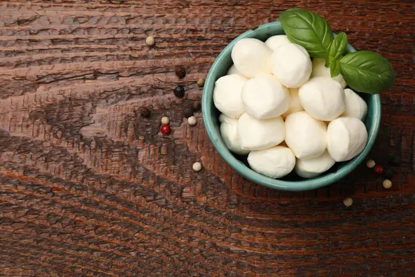 Kasede lezzetli mozzarella peyniri topları, ahşap masada biber ve fesleğen, üst manzara. Metin için boşluk