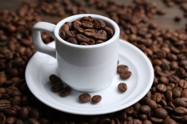 Aromatik kahve çekirdekleri, fincan ve çay tabağı masada, yakın plan.