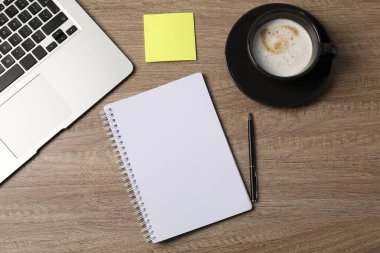 Not defteri, yapışkan not, kalem, kahve ve dizüstü bilgisayar ahşap masada, düz uzanıyordu.