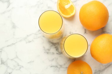 Bardakta portakal suyu ve beyaz mermer masada taze meyveler. Metin için boşluk
