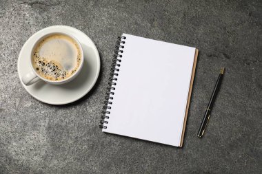 Defter, kalem ve kahve gri masada, düz yatıyordu.