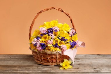 Tahta masada mercan zemin üzerinde güzel çiçeklerle dolu bir sepet.