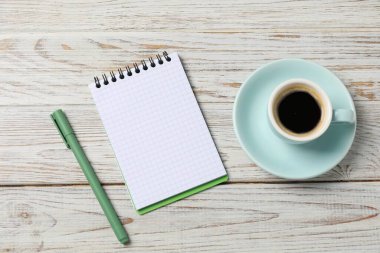 Beyaz ahşap masa üzerinde kalem ve kahve bulunan defter, üst manzara.