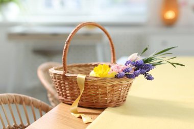 İçerideki masada güzel çiçekler olan hasır sepet.