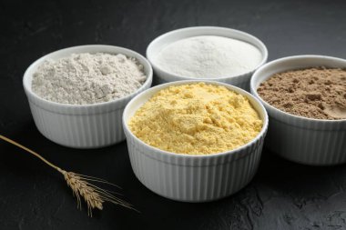 Kâselerdeki farklı un türleri ve siyah desenli masa, yakın plan.