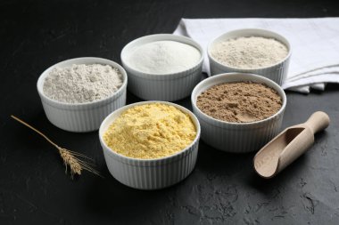 Kâselerdeki farklı un türleri, siyah desenli masada kepçe ve kazık.