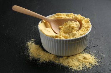 Mısır unu kasede ve kaşık siyah desenli masada, yakın plan.