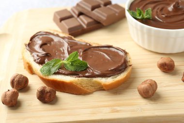 Çikolata kaplı lezzetli tost, fındık ve nane şekeri tahtada, yakın plan.