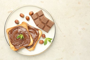 Lezzetli çikolatalı tostlar, parçalar, nane ve fındıklar ışık masasında, üst manzara. Metin için boşluk