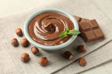 Lezzetli çikolata, parçalar, nane ve fındıklar ışık masasında, yakın plan