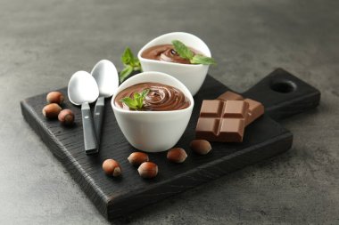 Lezzetli çikolata, parçalar, nane ve fındık. Gri desenli masa, yakın plan.