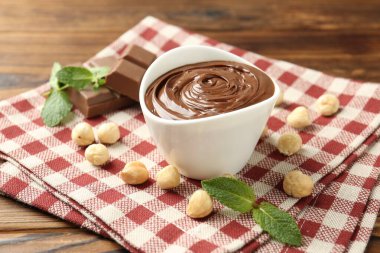 Lezzetli çikolata, parçalar, nane ve fındıklar ahşap masada, yakın plan.