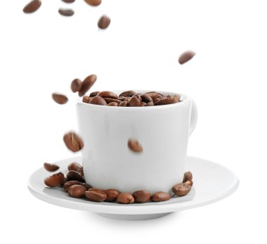 Kavrulmuş kahve çekirdekleri beyaz bardağa dökülüyor.