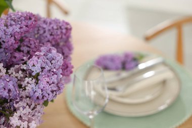 Güzel leylak çiçekleri, tabaklar, çatal bıçak takımı ve cam, yakın plan. Metin için boşluk