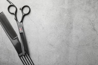 Kuaför aletleri. Makas ve tarak gri masaya, düz yere. Metin için boşluk