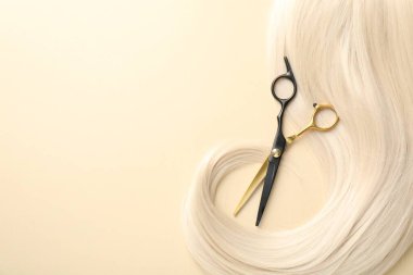 Bej arka planda saç tokası ve makas, üst manzara. Metin için boşluk