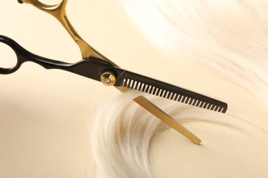 Bej arkaplanda saç tokası ve makas, yakın plan.