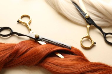 Bej arka planda saç kilitleri ve makas, yakın plan